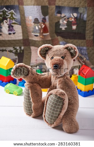 Teddy bear surrounded by blocks of children\'s plastic building kit on the background of the quilt