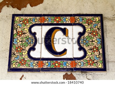 A found letter C, part of an entire alphabet, in the form of ceramic tiles, seen as a house number. Suitable for use as part of a headline or as a drop capital at the beginning of a paragraph.