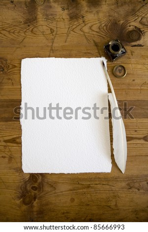 A blank sheet of handmade writing paper with quill pen and ink bottle ready to take type in the copy space.