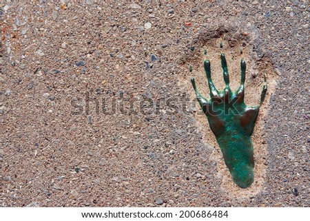 Red cobble pavement with a green metallic footprint, closeup, texture