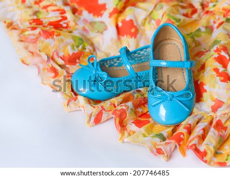 Pair of blue child`s shoes on red and yellow dress with chiffon. Dancing, hobby, free time concept. Selective focus. Card with copy space