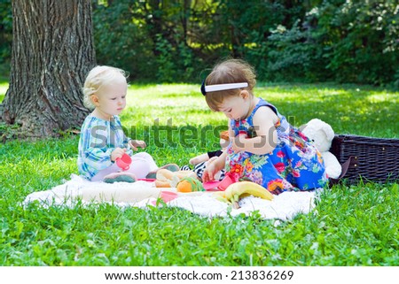Two friends toddler girls playing in park outdoor sitting on grass on meadow, summer day, childhood lifestyle concept