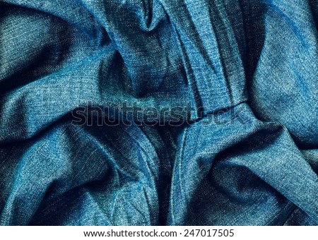 Closeup macro texture of blue jeans, clothing background with wrinkles and folds