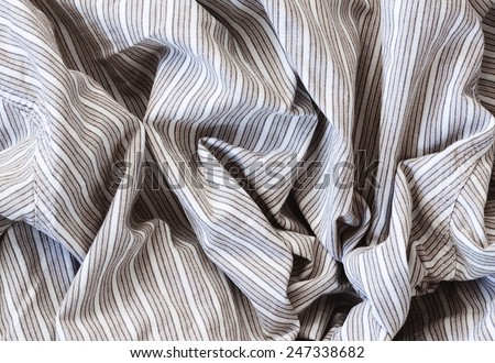 Closeup macro texture of linen cotton fabric with stripes, clothing background with wrinkles and folds