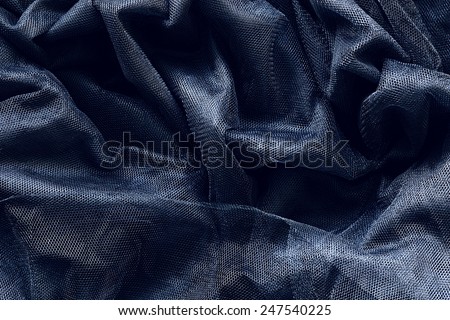 Closeup macro texture of black shiny smooth material fabric net lace, clothing background with wrinkles and folds