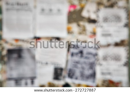 Blurred blurry soft focus closeup of old aged news board advertising pin board for commercials with pieces of old aged torn white paper, texture pattern background