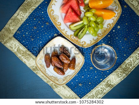 Fresh mixed fruit and sweet dates along with glass of drinking water shot from above. A healthy and nutritious food for breaking fast during holy month of Ramadan.