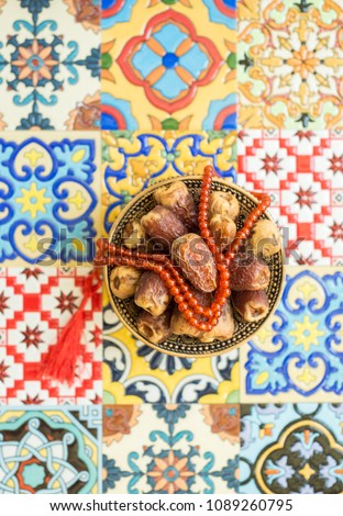 Arabian best quality dates and Islamic Subah - prayer beads on moroccan tile background. Ramadan Kareem greeting background.