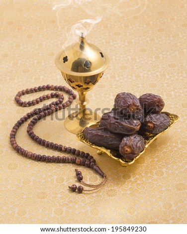 An oudh burner, prayer beads and dates