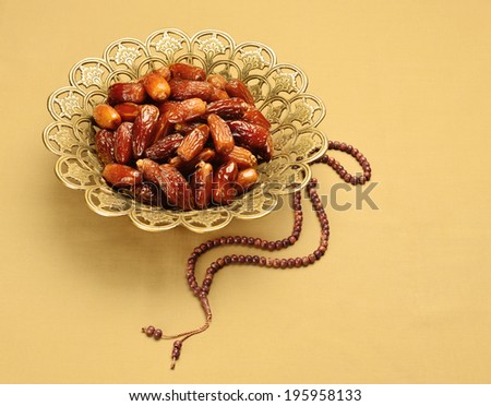 An ornamental bowl of dates and  prayer beads