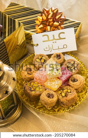 \'Eid Mubarak\' message in arabic script on a tag along with gift packs and assorted sweet