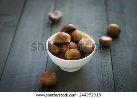 Non-roasted chestnuts in a white bowl -over the shoulder view