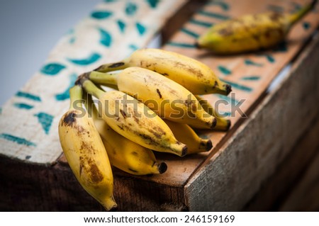 Bunch of Indian small bananas displayed on a wooden box in the market.