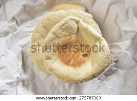 Arabic flat breads placed on wrinkled white paper.