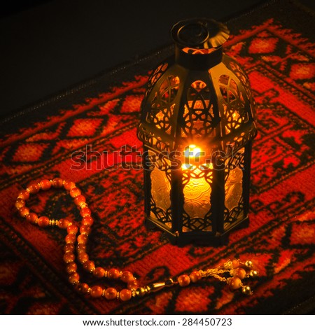 Ramadan greeting card background. An illuminated lamp on bright red carpet background.