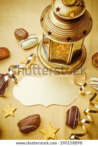 An empty golden seal to write headline. Ramadan lamp, date chocolates and confetti background.