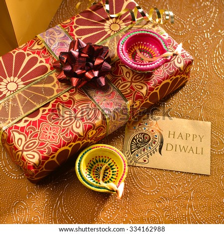 \'Happy Diwali\' message on a tag along with gift box and lamps. Indian festive background.