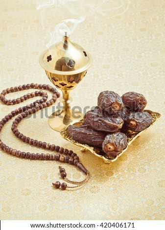 Aromatic oud burning in the burner, placed along with sweet arabian dates and islamic prayer beads. Muslim religious objects.