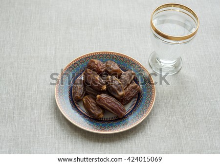 Basic food and drink to break Ramadan fast. Sweet and nutritious date fruits and glass of pure drinking water.