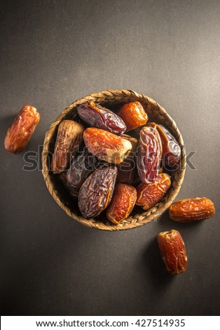 Sweet and ripen dates in basket. Most common and popular fruit in Arabian countries. Top view on dark background.