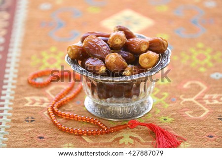 Arabic dates in a glass bowls and muslim prayer beads. Ramadan stock photo.