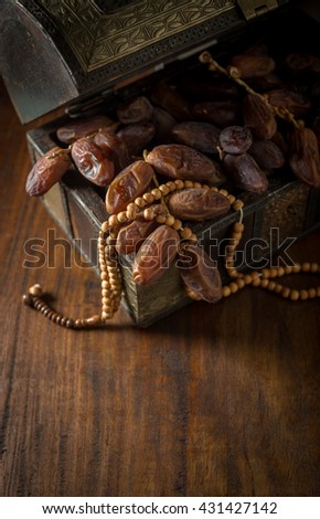 Fine quality Arabian dates stored in antique wooden trunk with Islamic prayer beads. Ramadan food and objects.