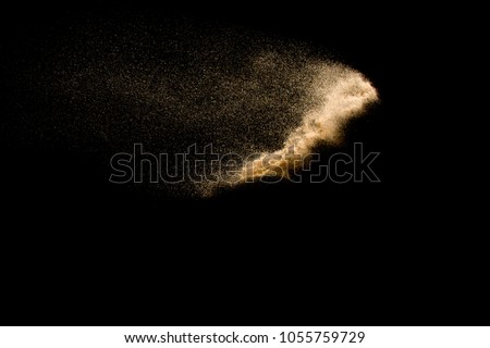 Golden sand explosion isolated on black background. Abstract sand cloud. Golden colored  sand splash against  dark background. Yellow sand fly wave in the air.