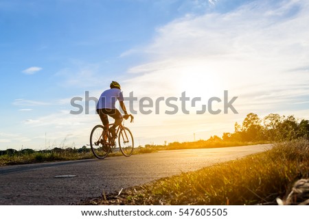 Silhouette of cyclist in motion on the background of beautiful sunset. A man ride a bike in evenning.