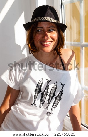 Beautiful lisbon girl dressing a white shirt with fishes and black hat, smiling