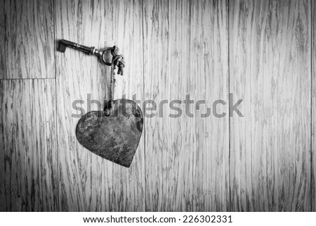 Magic key with metal heart on wooden background - Black and white