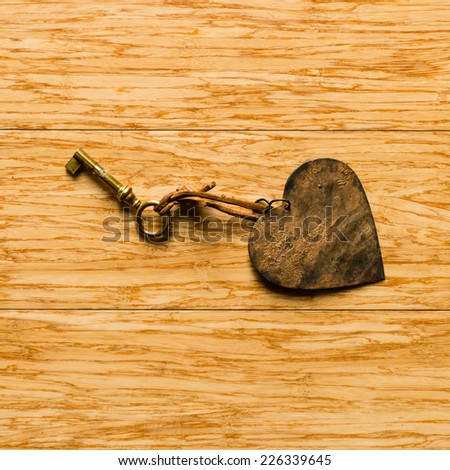 Magic key and metal heart on wooden background