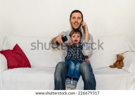 Baby and father watching tv on a white sofa while baby is crying