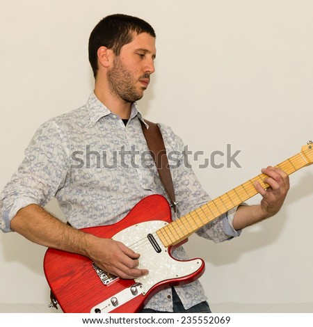 Guy playing red electric guitar