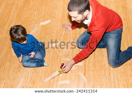 Baby and father playing with train on the floor