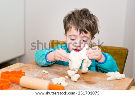 Cute caucasian baby making bread on a wooden table
