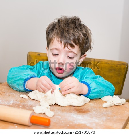 Cute caucasian baby making bread on a wooden table