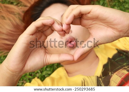 hands in womanÃ¢Â?Â?s heart-shaped with kiss mouth behind