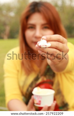 girl eating ice cream and point her spoon filled of ice cream in front of her face in blurry focus