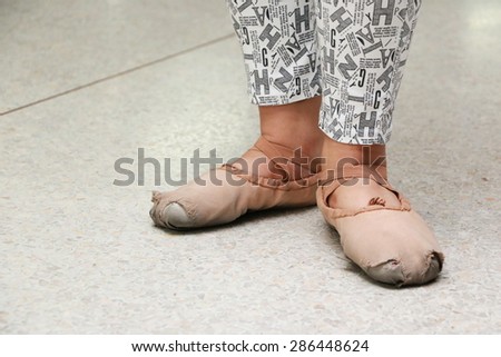 a girl wears old used ballet shoes learning ballet