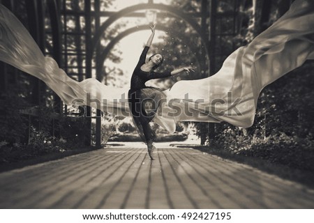 Ballerina out of doors, young modern ballet dancer posing. Black and white photography. The fabric in the air
