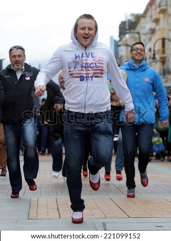 Sofia, Bulgaria - March 8, 2014: Men run with ladies shoes on high heels to support women victims of domestic and sexual violence as part of the international Walk a Mile in Her Shoes campaign.