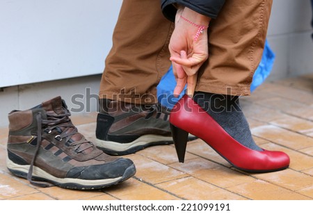 Sofia, Bulgaria - March 8, 2014: Man puts on ladies shoes on high heels to support women victims of domestic and sexual violence as part of the international Walk a Mile in Her Shoes campaign.