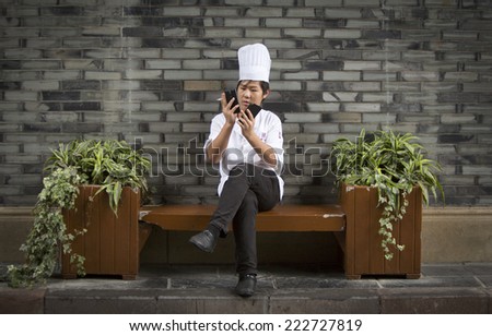 Sichuan, China - August 8, 2014: Chinese cook is checking his two phones during his break for a cigarette near the restaurant he is working in.