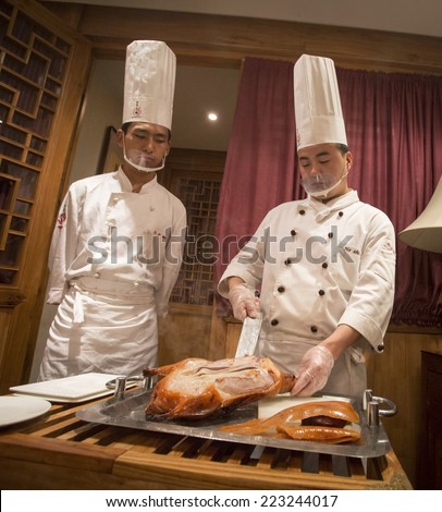 Beijing, China - August 6, 2014: Chef and cook are cutting roasted duck in a restaurant in Beijing.
