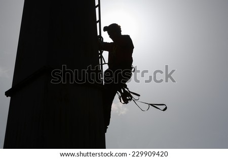 Silhouette of a person climbing a cabin lift pillar.