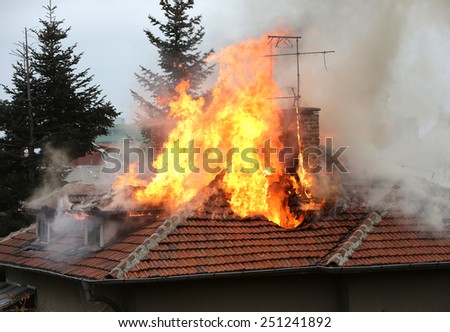 A house roof on fire and smoke.
