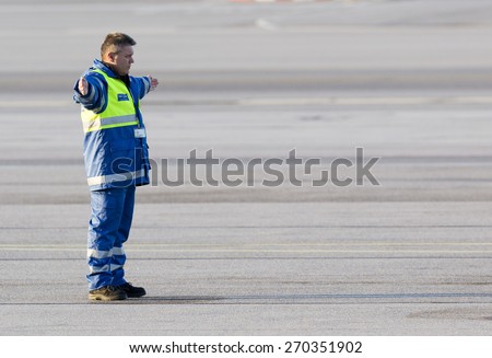 Sofia, Bulgaria - April 11, 2015: An airport worker is navigating the movement of an airplane on the airport runway after landing.