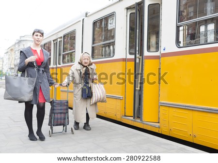 Budapest, Hungary - April 30, 2015: An young woman is helping an old lady to get on the trolley car number 47 at its last staition in Budapest, Hungary