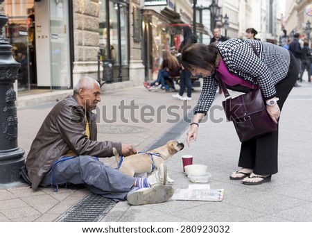 Budapest, Hungary - April 30, 2015: An old man is begging in front of a fashion shop in a main street in Budapest, Hungary.