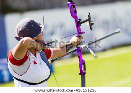 An young girl is shooting with a recurve bow during un open archery competition.